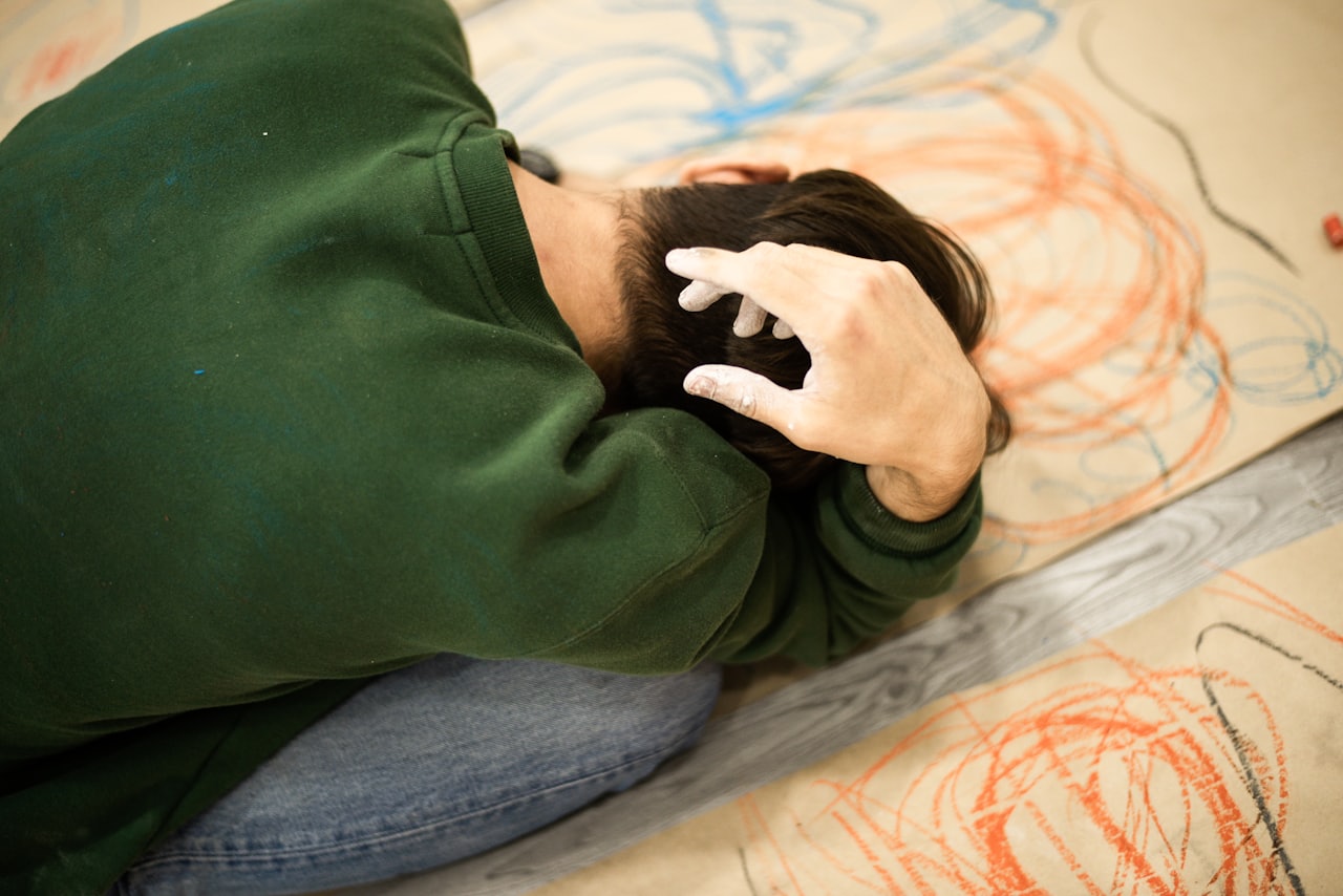 A picture of a teenager on the autism spectrum laying on the flood coloring with crayons on cardboard.